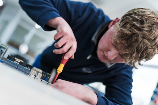 Elektrotechnik Auszubildender mit einem Schraubenzieher in der Hand