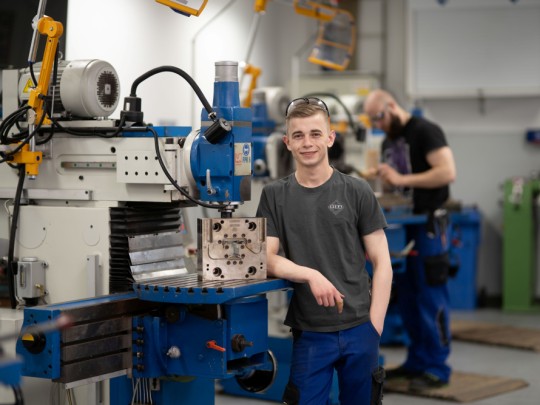 Werkzeugmechaniker Azubi der VEKA AG an einer Maschine stehend in Sendenhorst