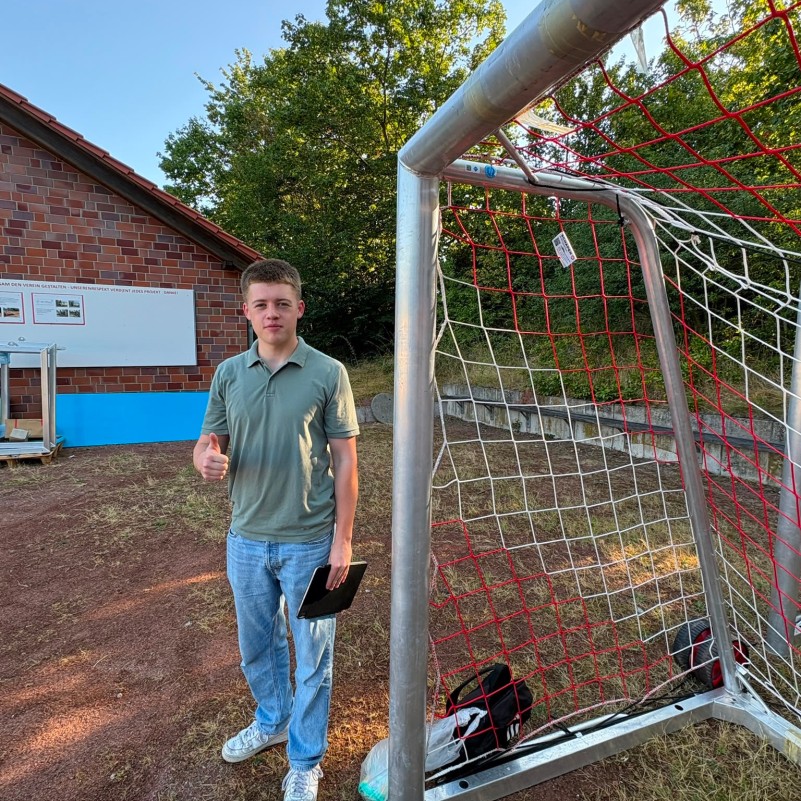 Simon Grosse vor einem Fußballtor mit QR Code