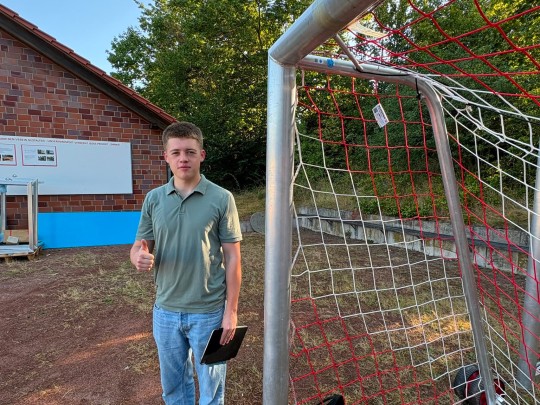 Simon Grosse vor einem Fußballtor mit QR Code